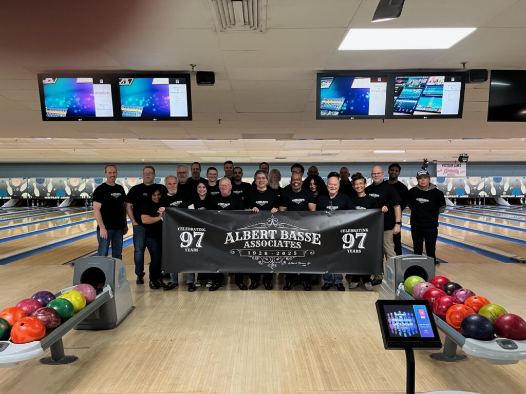 image captures a celebration of Albert Basse Associates' 97th anniversary at a bowling alley