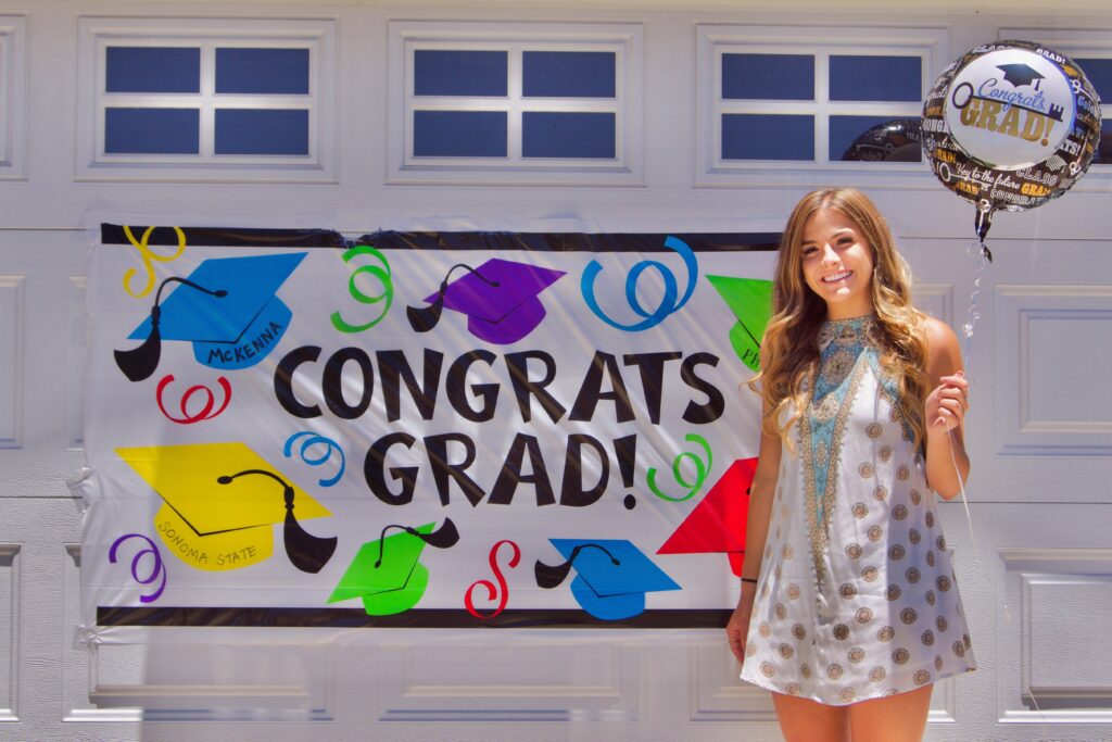 image features a young woman standing in front of a garage door, celebrating a graduation